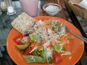 The salad with bread roll and smoothie and dressing in background